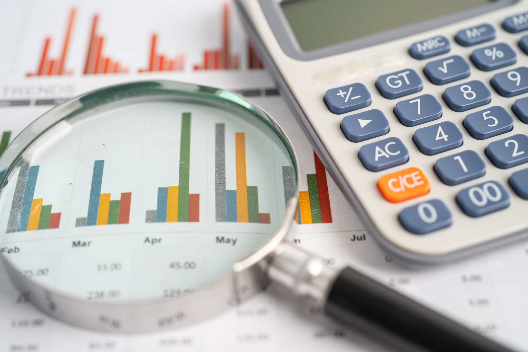 Magnifying Glass and Calculator on Charts Graphs Paper. Financia